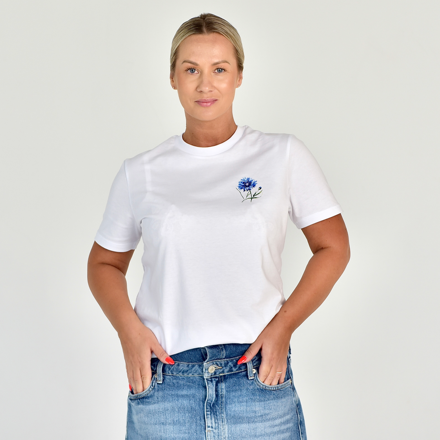 Balti marškinėliai su mažu mėlynos rugiagėlės piešiniu. Stilingas ir unikalus dizainas, puikiai tinkantis vasaros sezonui. Designedbyme.lt originalus kūrinys, atspindintis gamtos grožį ir modernumą, Moteriški marškinėliai, Vasaros kolekcija, Naujausi dizainai