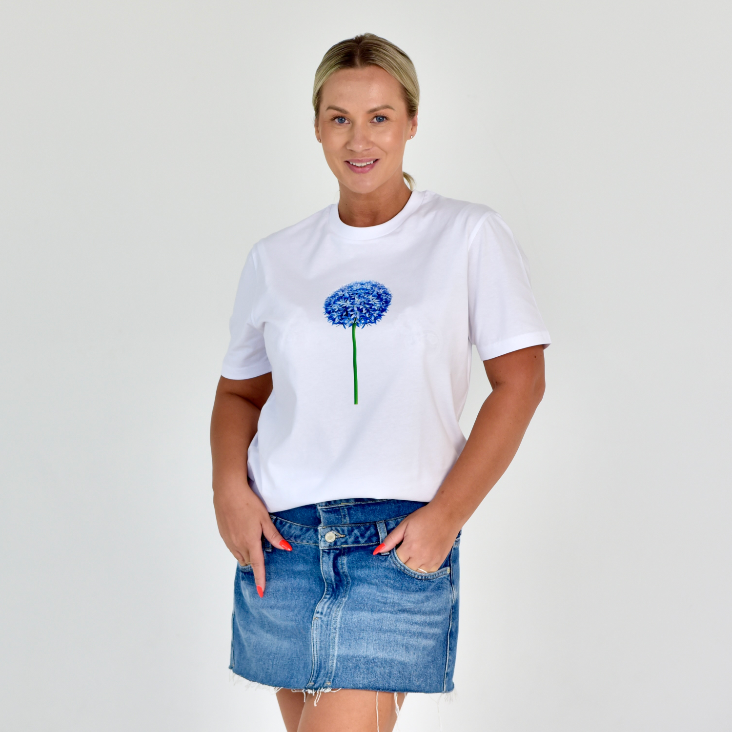 Stilingi balti moteriški marškinėliai su mėlynu česnako žiedo atvaizdu, simbolizuojantys gamtos grožį ir unikalumą. Designedbyme.lt originalus dizainas, puikiai tinkantis kasdienai ir ypatingoms progoms. Moteriški marškinėliai, Vasaros kolekcija, BESTSELLER'iai, Naujausi dizainai